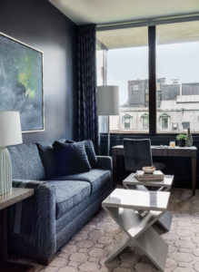 Navy blue walls, dramatic walls, dark walls, monochromatic living room, silver geometric bunching tables, navy blue sofa, home office, den, semi-gloss walls, abstract art