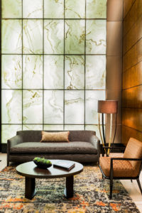 Backlit white onyx, backlit stone, statement wall, translucent stone, warm light, contemporary wood paneled wall, wood paneling, abstract rug, commercial project, boston, hotel, common space, lobby