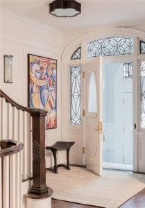 Foyer, entry way, modern art, abstract art, flush mount light, applied moulding, arched doorway, staircase, banister, baluster, white front door, wrought iron window detail, transitional foyer