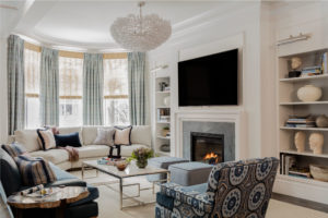 transitional living room, transitonal family room, applied wall moulding, wood burning fireplace, transitional fireplace surround, neutral color palatte living room, blue and white living room, wall niche, floor legnth drapery, custom drapery, built in bookcase, transitional chandelier, custom sectional sofa