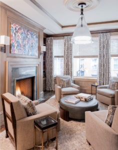 Study, den, living room, wood paneled walls, wood paneling, fireplace surround, custom millwork, applied moulding, ceiling soffit, round leather ottoman, abstract art, transitional design
