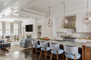 transitional kitchen, globe pendants, glass pendants, kitchen island lighting, white kitchen, white kitchen cabinets, blue upholstered counter stools, counter stools with back, open concept floor plan, transitional living room, transitonal family room, applied wall moulding, wood burning fireplace, transitional fireplace surround, neutral color palatte living room, blue and white living room, wall niche, floor legnth drapery, custom drapery, built in bookcase, transitional chandelier, custom sectional sofa