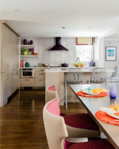 Purple range hood, eggplant purple range hood, grey subway tile backsplash, contemporary kitchen island, colorful accents, fun kitchen, open kitchen shelving, fully integrated refrigerator,