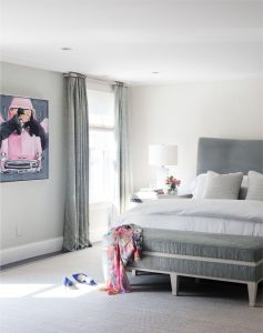 Transitional master bedroom, gray upholstered headboard, upholstered end of bed bench, pink punch color, floor to ceiling drapery