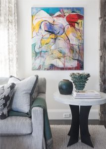Reclaimed wood beams, decorativ beams, wallmounted television, modern rustic living room, transitional living room, wicker back lounge chair, transitional iron chandelier, colorful abstract art