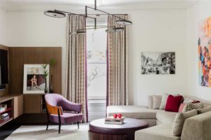 black and white photography,colorful artwork,crown moulding,flat panel millwork,modern artwork,modern chandelier,sectional sofa,statement color,Transitional Drapery,transitional millwork