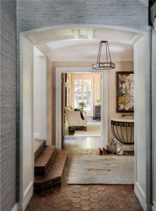 transitional foyer, front entry design, demilune table, neutral grasscloth wallpaper, blue grasscloth wallpaper, natural grasscloth wallpaper, natural stone floor, stone tile floor, transitional glass chandelier, arched doorway, arched passthrough, cased archway
