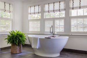transitional master bathroom, soaking tub, freestanding tub, interior shutters, custom bathroom curtains, natural stone bathroom floor, stone tile floor