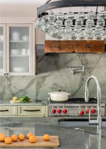 transitional kitchen, transitional chandelier, blown glass chandelier, marble backsplash, exposed beams, modern rustic kitchen, reclaimed wood range hood, glass kitchen cabinet doors, grey kitchen cabinets, pot filler faucet