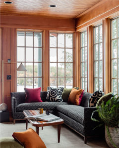 sun room, transitional sunroom, transitional sectional sofa, colorful accent pillows, vintage coffee table, retro coffee table, wood paneled walls, wood paneled ceiling