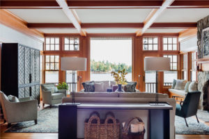 modern rustic lakehouse, transitional living room, contemporary area rug,lakehouse,lakeside view,living room furniture,media cabinet,nailhead trim,relaxed living room,stained moulding,stone fireplace surround,transitional storage cabinet,velvet side chair,warm wood,window bench,wood beams,wood flooring,wood panel wall,wood paneling