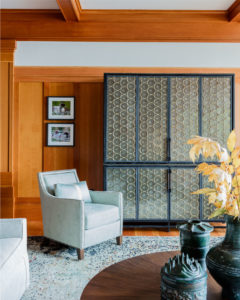 transitional family room, decorative interior columns,lakehouse,lakeside view,transitional living room furniture,media cabinet,nailhead trim,relaxed living room,stained moulding,transitional storage cabinet, transitional area rug, warm wood,wood beams,wood flooring,wood panel wall,wood paneling