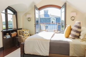 modern poolhouse bedroom, transitional bedroom, french doors to balcony, french doors in bedroom, subtle beach theme bedroom, custom millwork, built in bedroom storage, transitional wall sconces