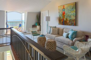 beach house loft space, transitional beach house, white wicker chair, neutral sofa, wicker drum tables, interior french doors, loft space with balcony,