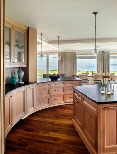 transitional kitchen, curved kitchen cabinets,large kitchen island,ocean view,warm wood in kitchen, glass panel kitchen cabinets, single lite kitchen cabinets