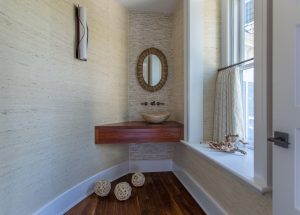 neutral grasscloth wallpaper, café curtain in powder room, transitional powder room, round bathroom mirror, dark hardwood flooring, basin sink, vessel sink, wall hung faucet, small bathroom design