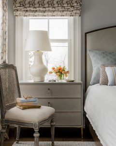 antique chair, traditional side chair, chest of drawers, nightstand, night table, ceramic table lamp, white table lamp, upholstered headboard, white bedding, decorative pillows, bed pillows, white bedding, roman shade