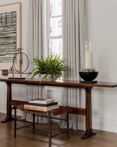 wall art, sculpture, wood console table, leather stool, wrought iron frame, curtain panels, wood floor